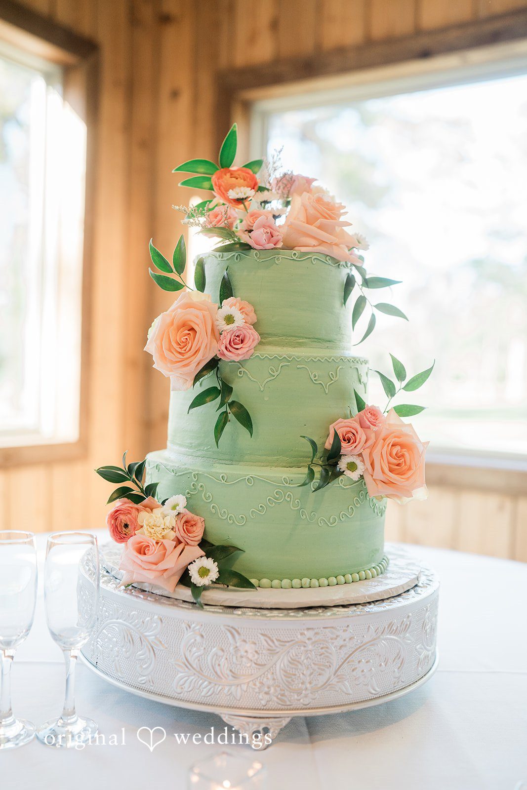 A beautiful sage green cake adorned with delicate blooms