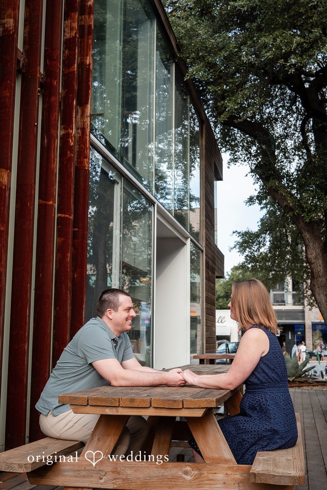 Eric + Kimberly Engaged couple sitting across from each other at a wooden picnic table