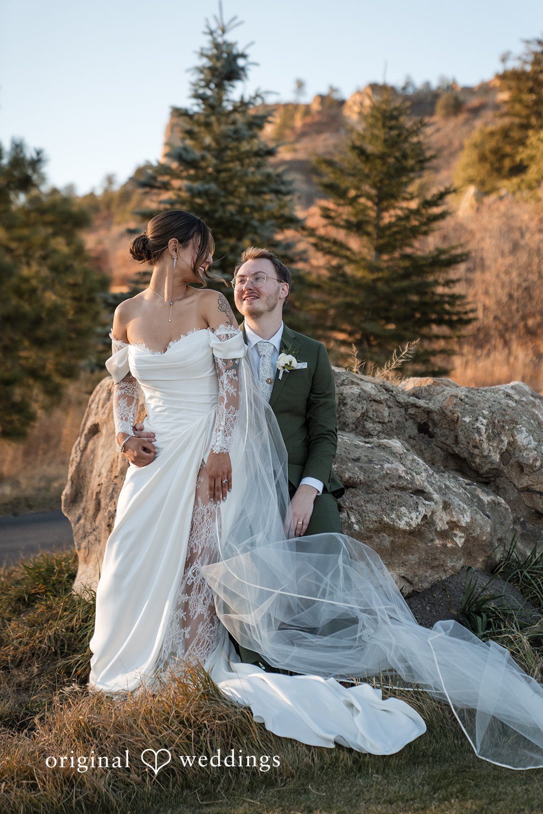 Bride and groom posing together on a large rock outdoors