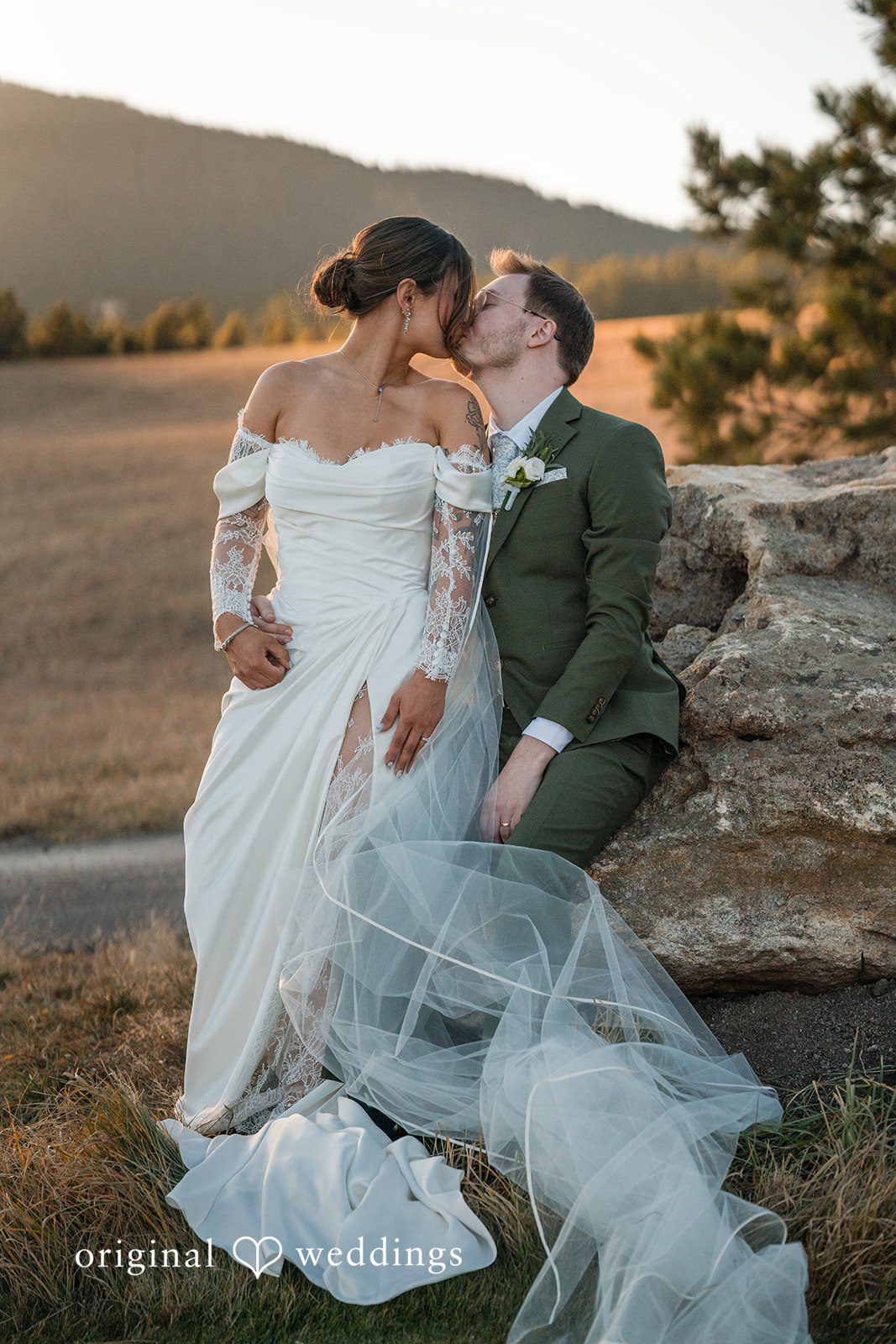 Couple sitting together on a rock during outdoor wedding portraits