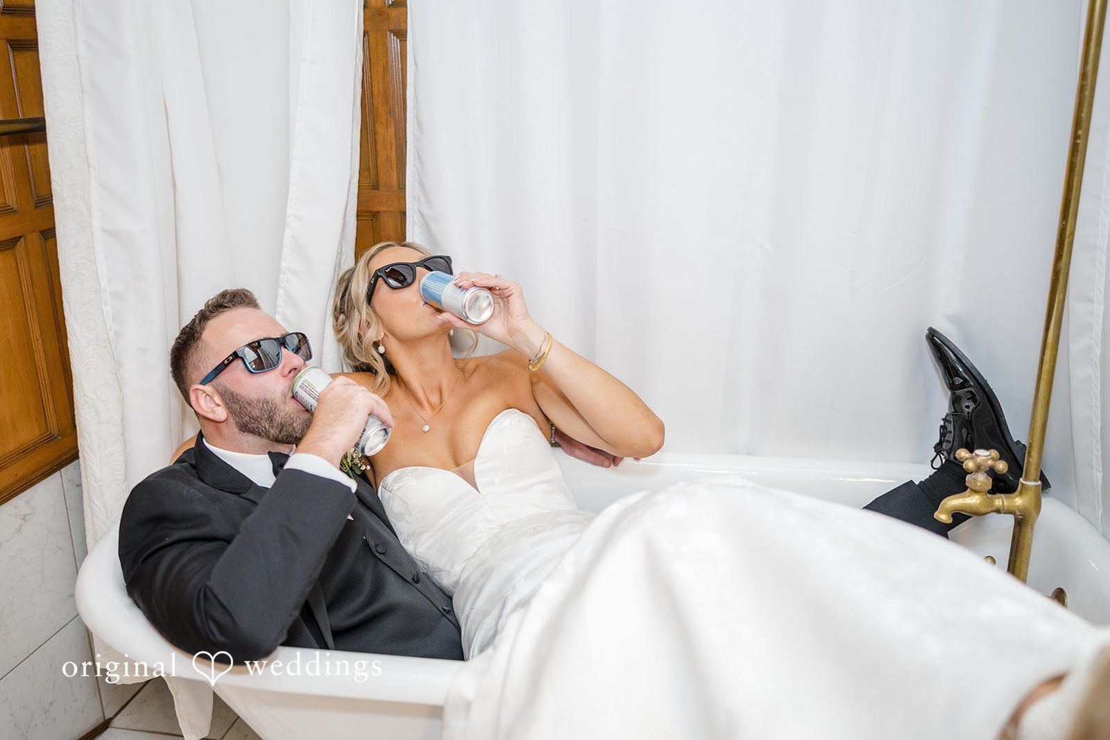 Laura + Nicholas Bride and groom relaxing in vintage bathtub while drinking