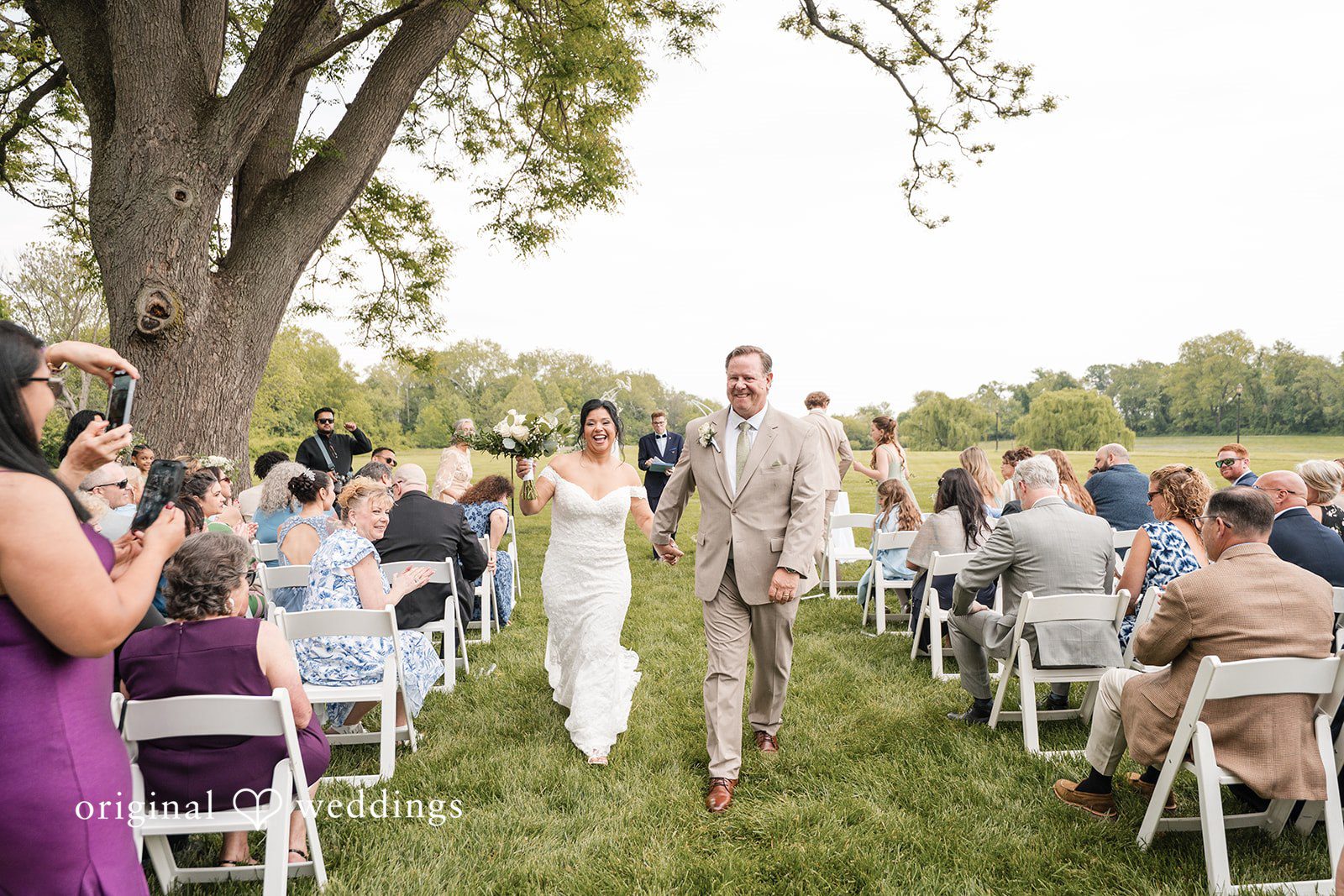Baltimore Wedding Photographers capturing couple walking out of ceremony smiling at Swan Harbor Farm by Original Weddings