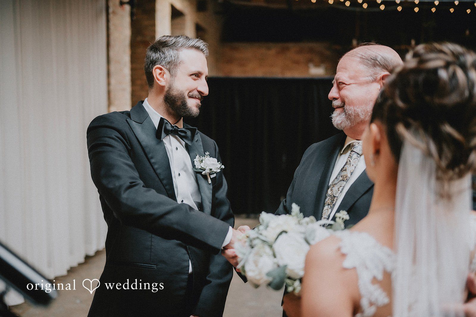 The groom and bride's father exchange handshake