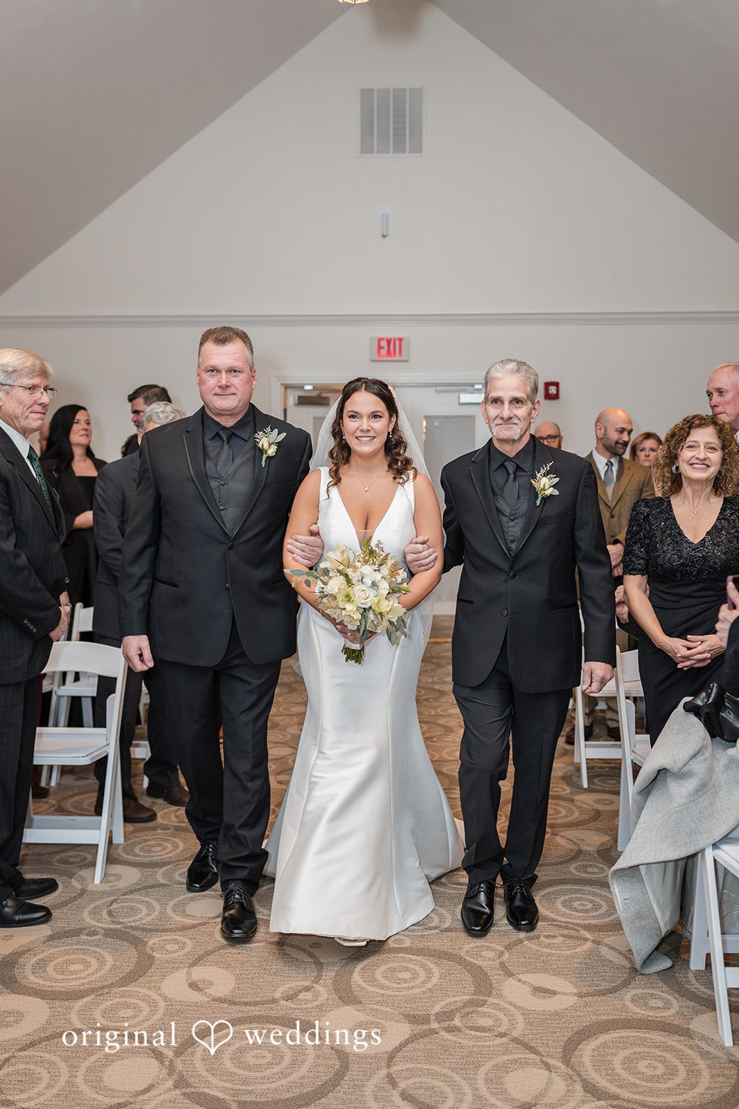 Lovely picture of bride walking down the aisle arms in arms with her companions