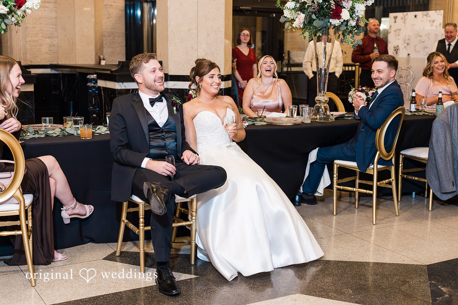 Couple seated at reception holding glasses at The Carlisle Room
