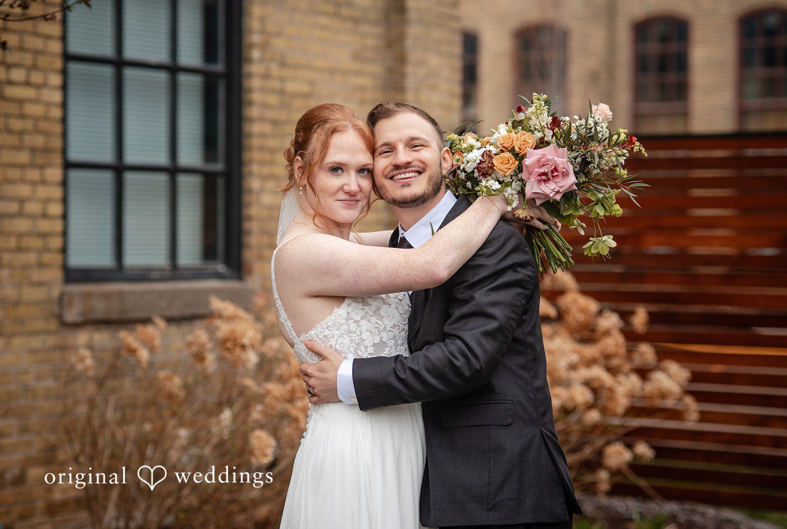 Minneapolis wedding photography by Original Weddings capturing couple hugging and looking toward camera at The Essence Event Center