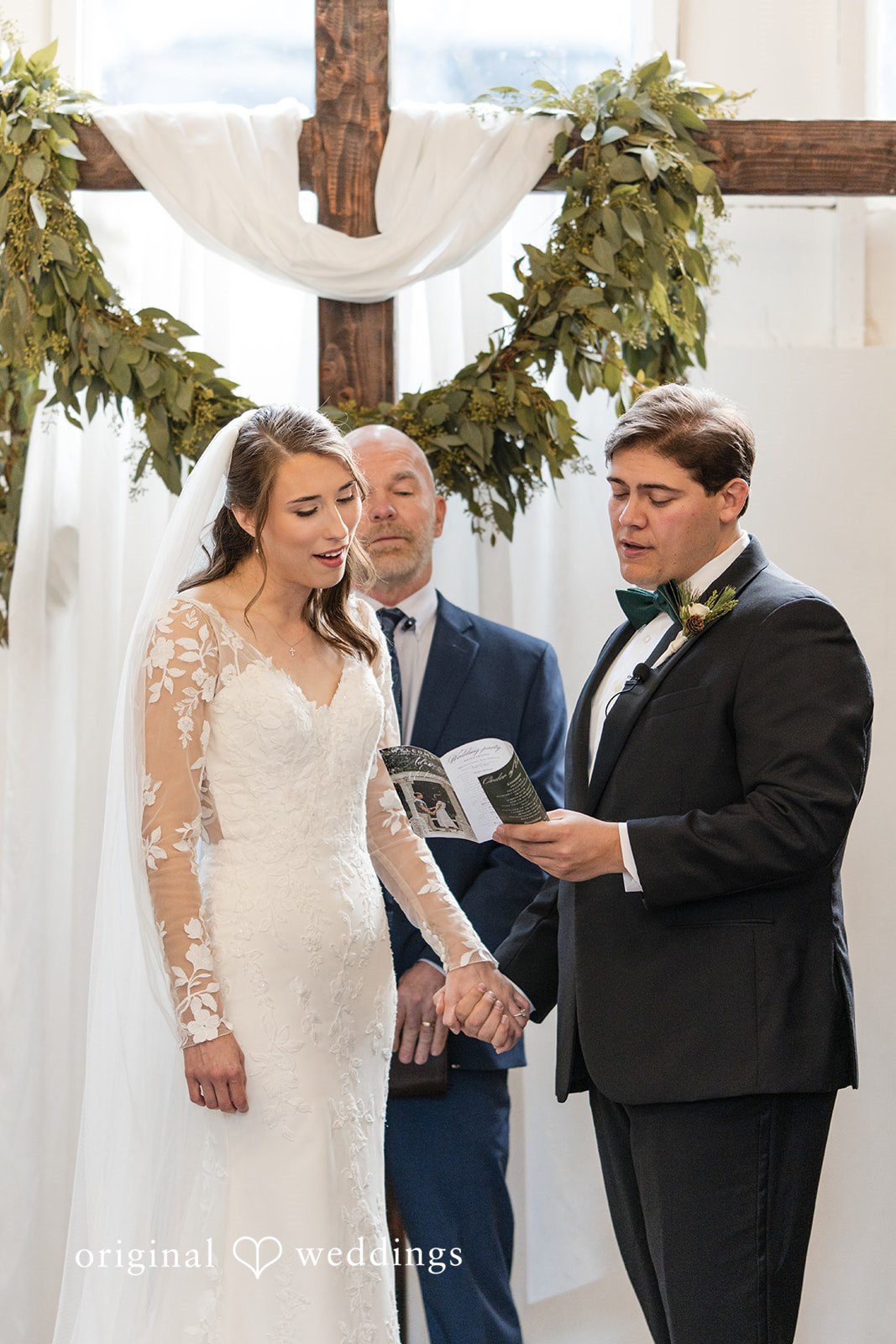 Adam + McKenzie Couple exchanging vows during ceremony under decorated cross