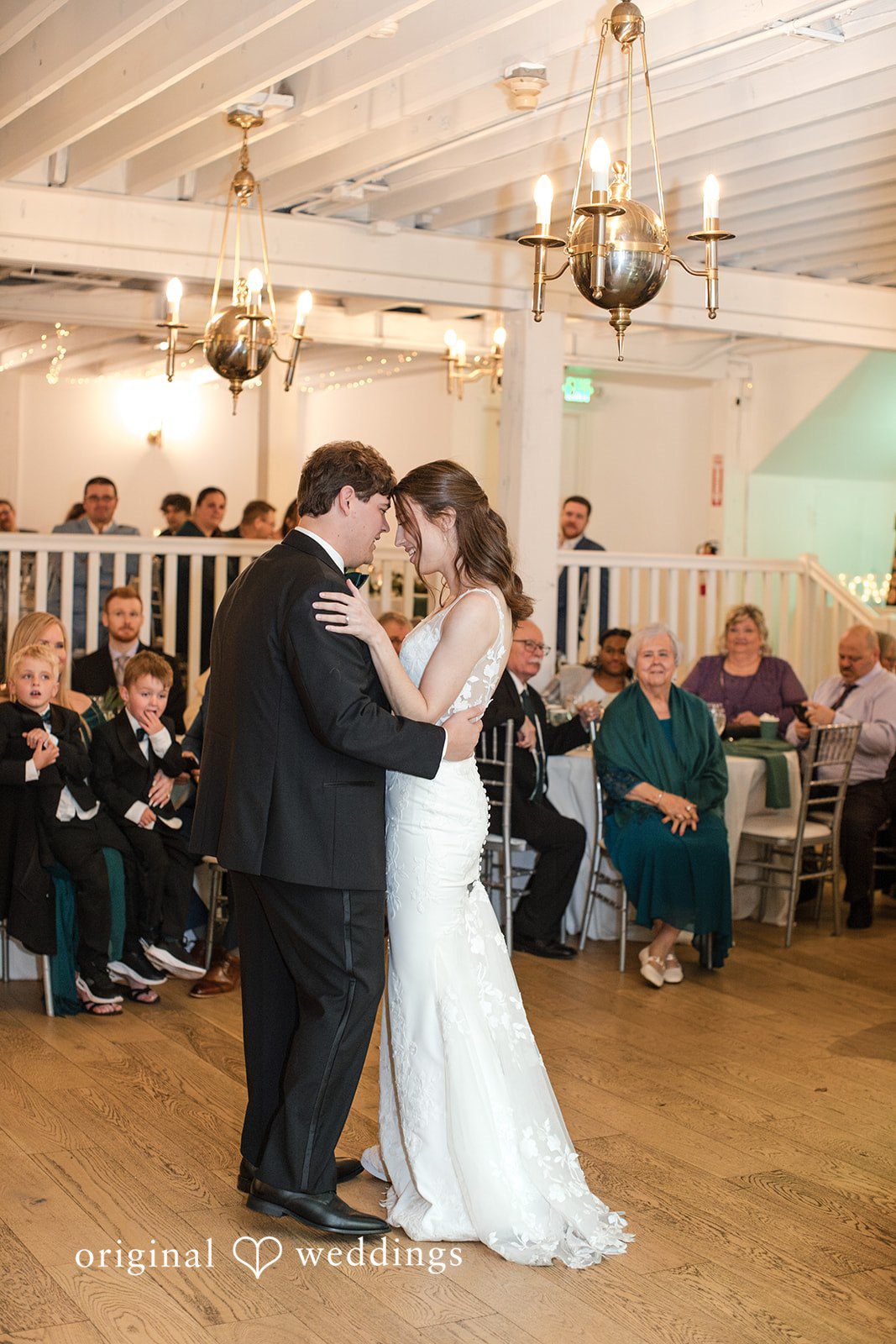 Adam + McKenzie First dance moment in reception hall with wooden floors and warm lighting