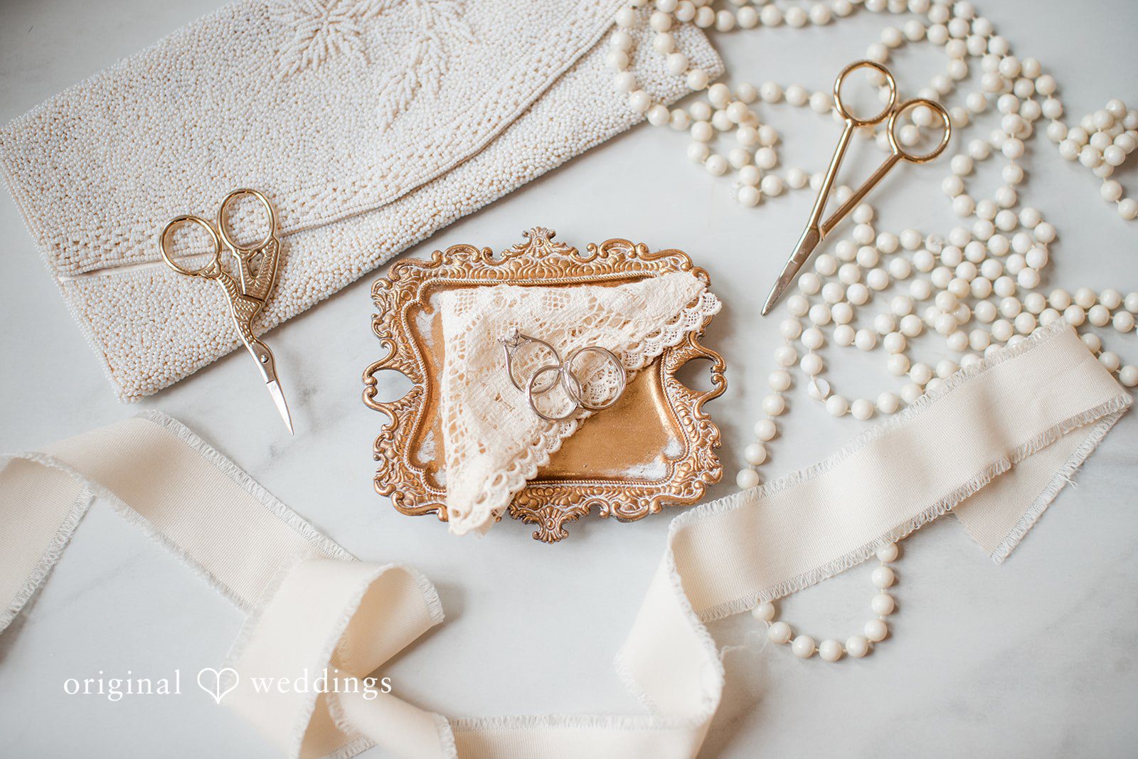 Adam + McKenzie Bridal detail flat lay with jewelry, shoes, and invitation suite in soft neutral tones