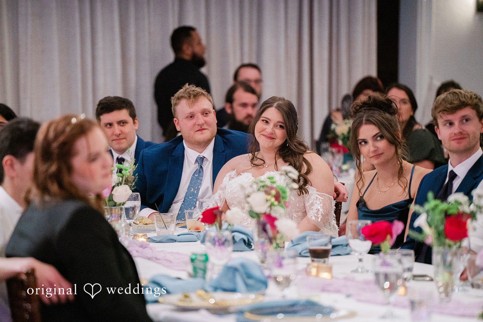 The couple seated with their wedding party at their wedding reception