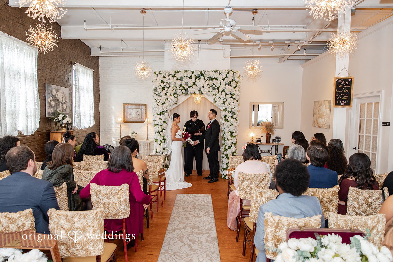 Amanda + Emmanuel Perspective view down a wedding ceremony aisle filled with seated guests.