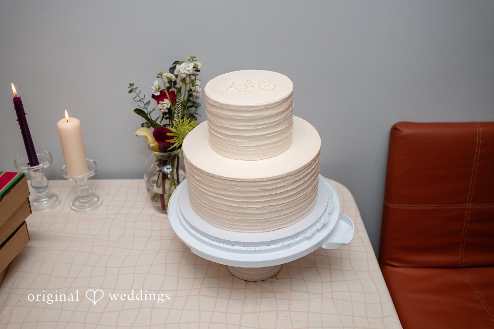 Amanda + Emmanuel White multi-tiered wedding cake displayed on a table.