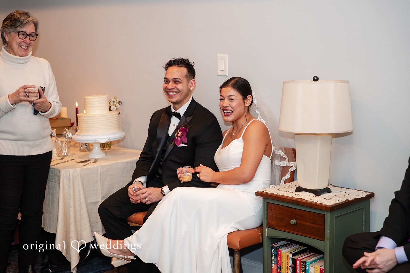 Amanda + Emmanuel Bride and groom sitting together near a small cake setup.