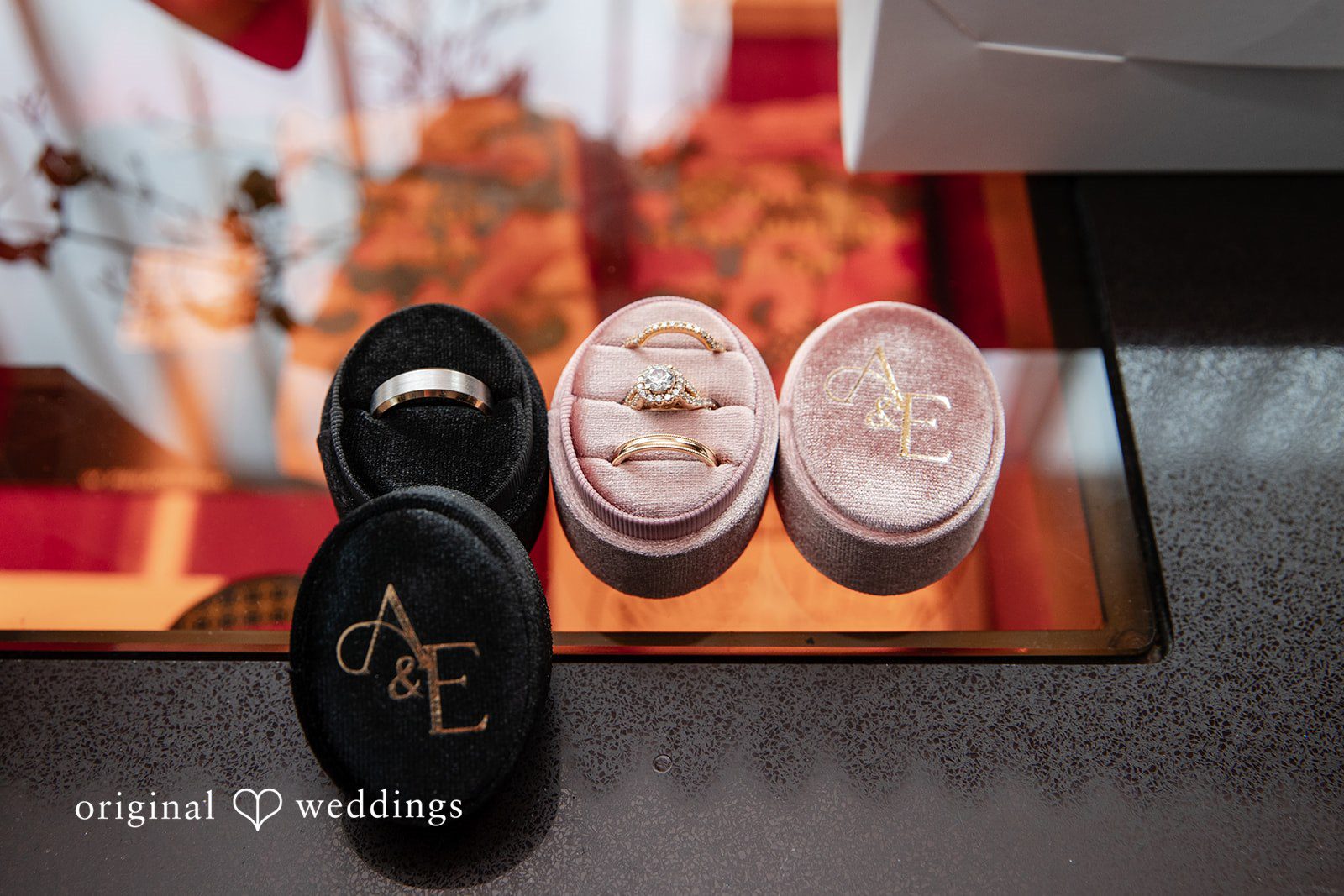 Amanda + Emmanuel Close-up of open wedding ring boxes on a tray.