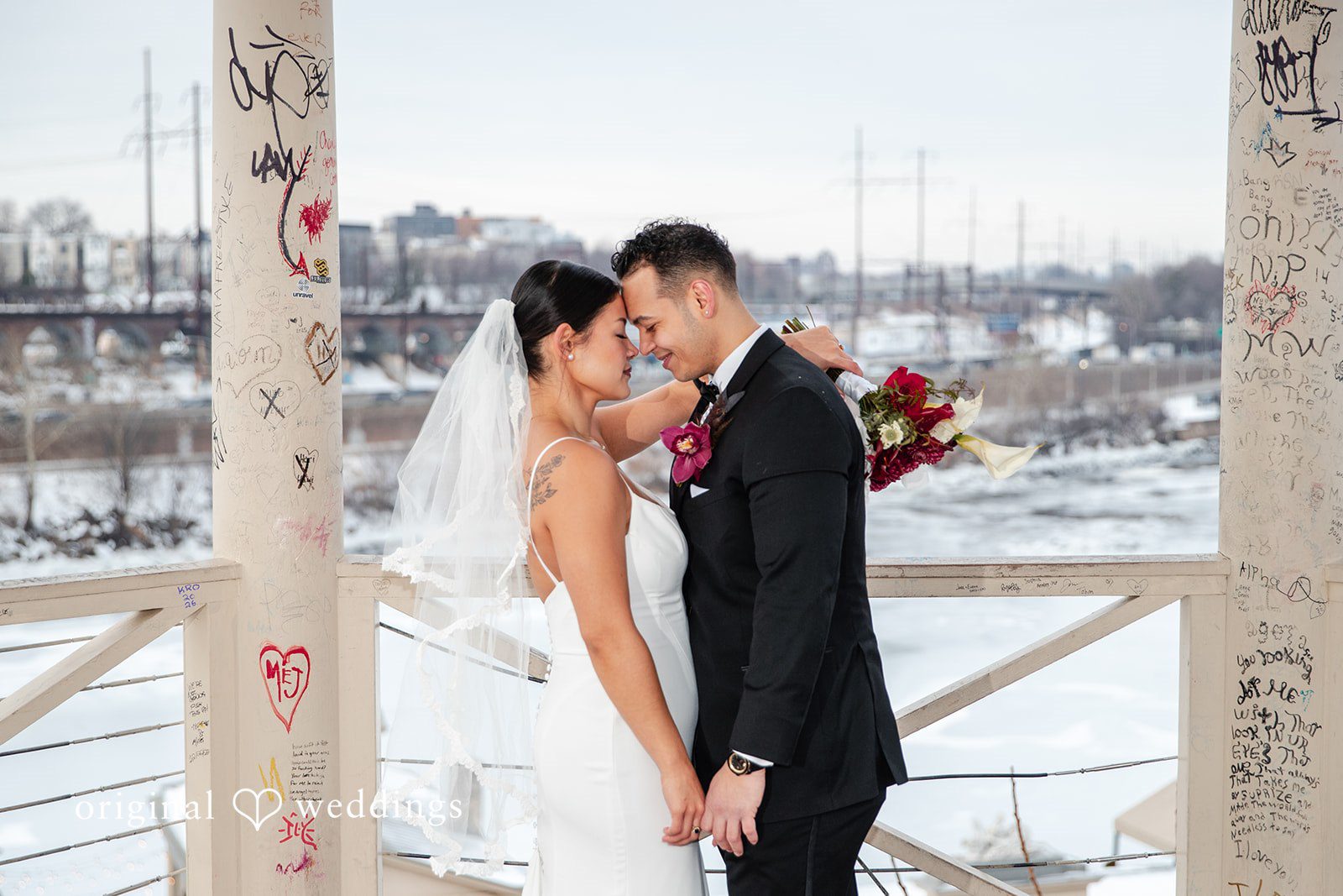 Amanda + Emmanuel Bride and groom holding hands and leaning in close within a structure.