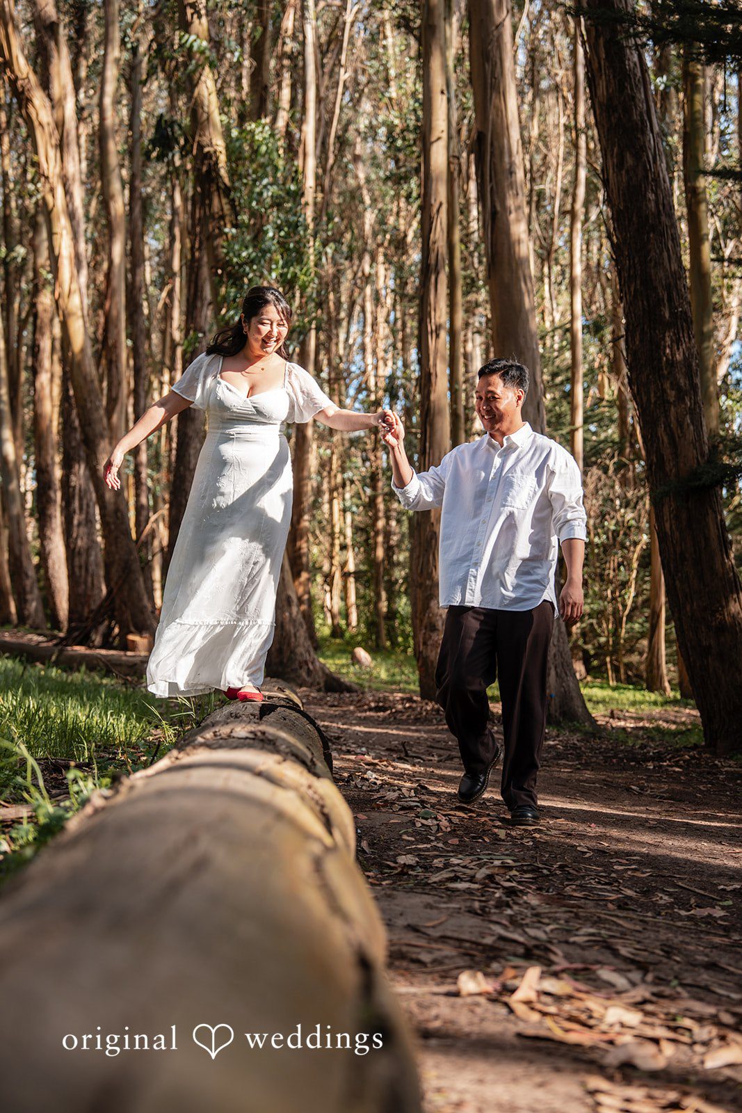 Playful couple balancing on a log at The Presidio