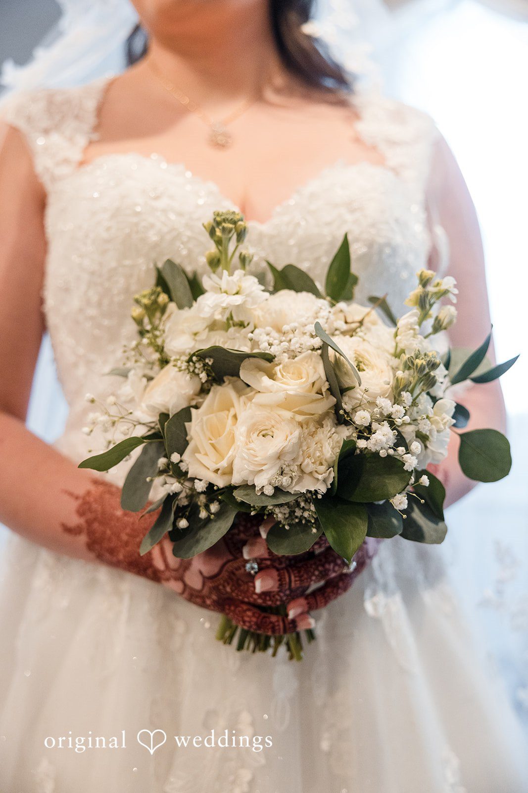 Close-up bridal detail featuring bouquet and wedding dress