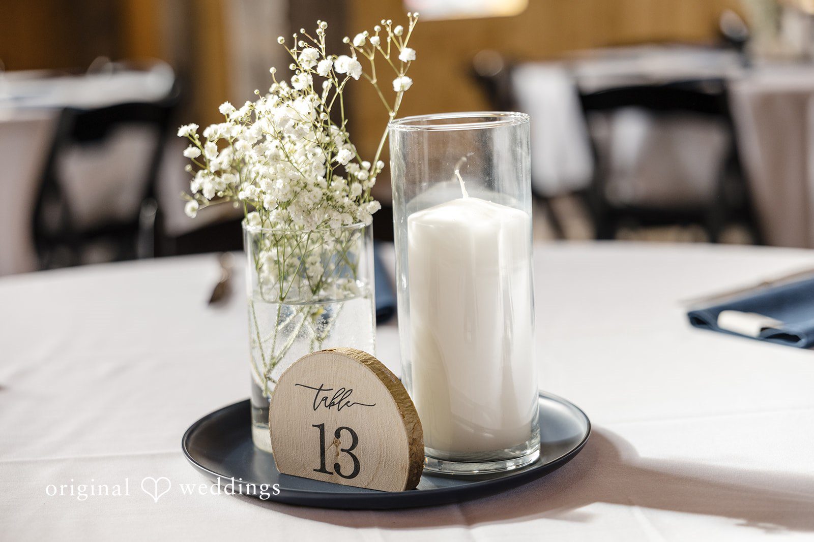 Alia + Lance Wedding centerpiece featuring a white candle, baby's breath, and a wooden table number.