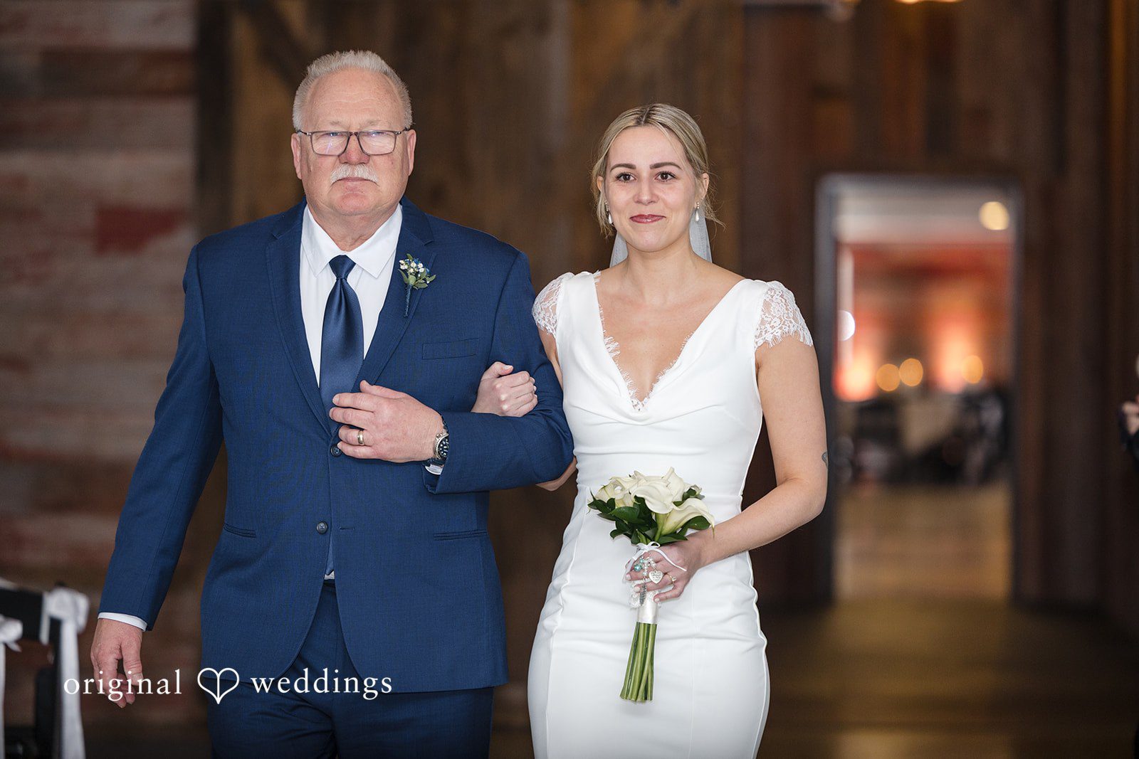 Alia + Lance Bride walking down the aisle arm-in-arm with a man in a navy suit.