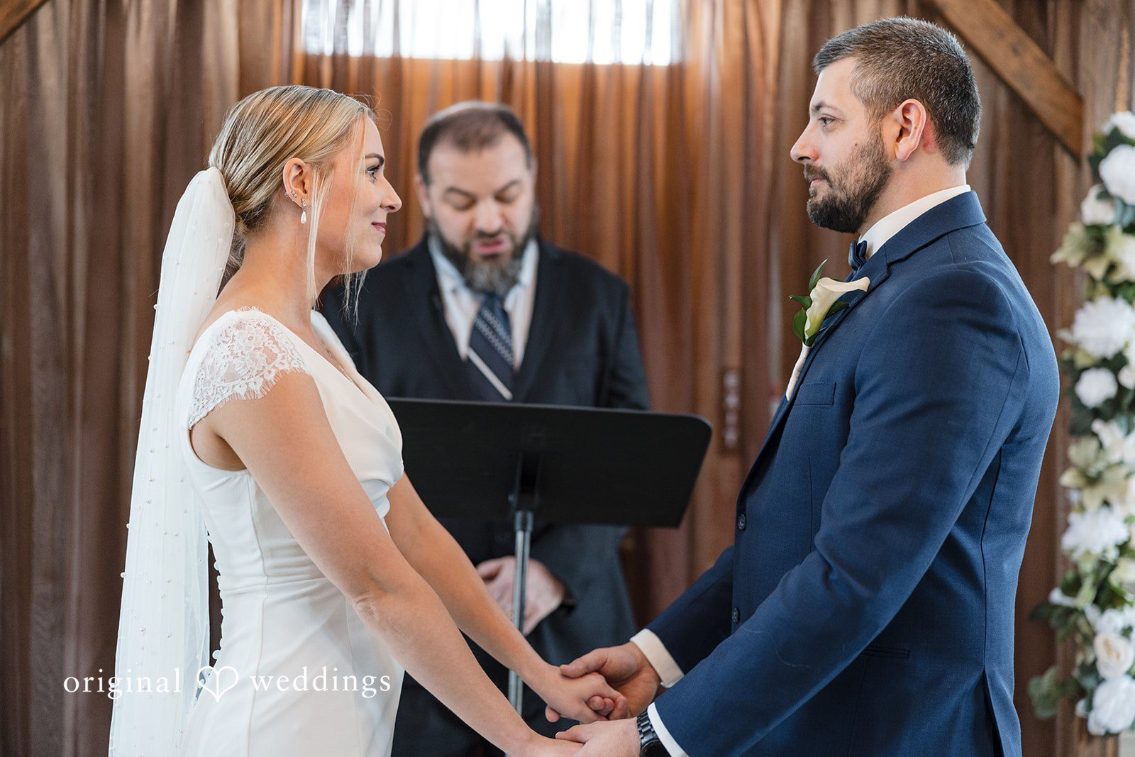 Alia + Lance Bride and groom holding hands during their wedding ceremony at The Village Barn.