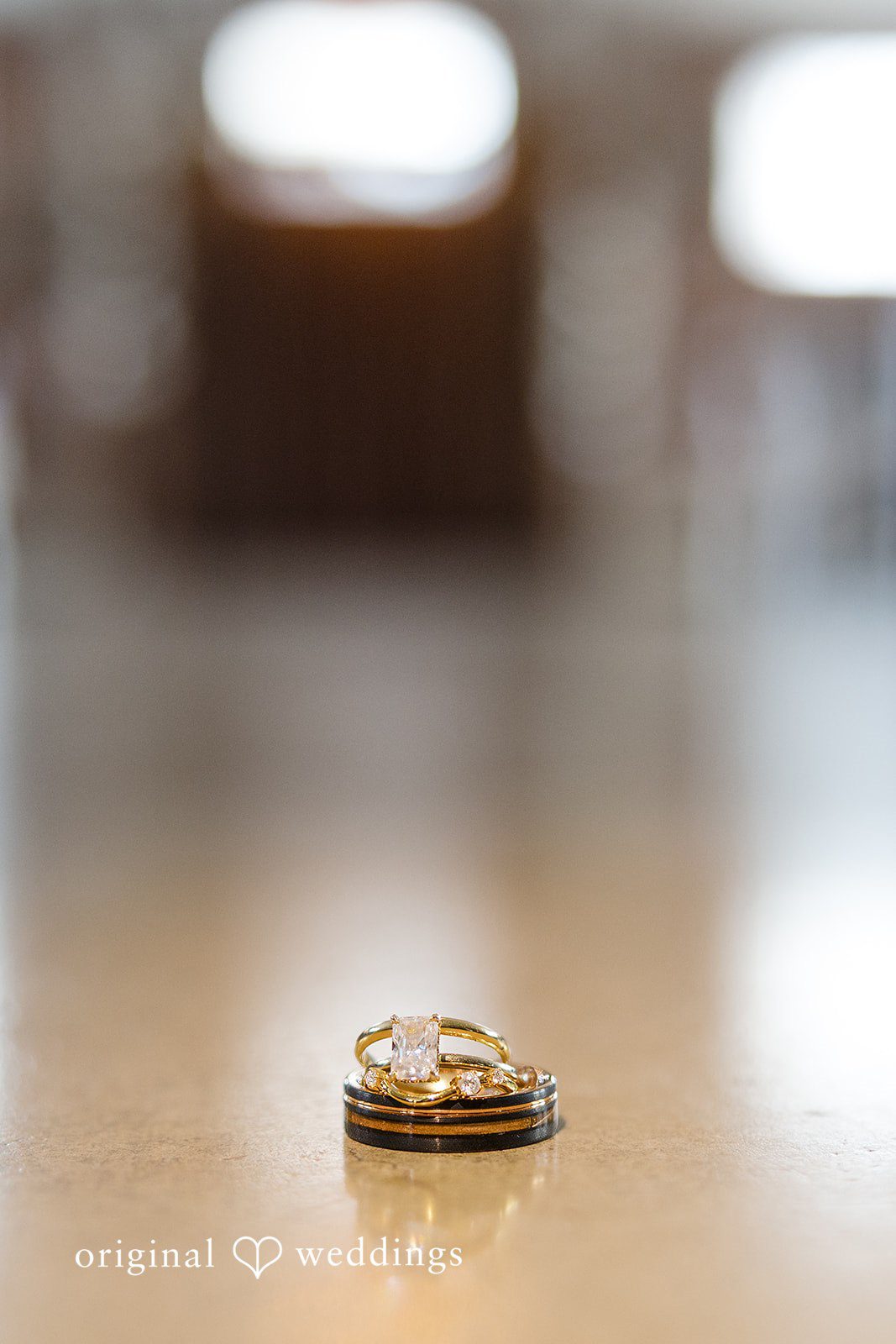 Alia + Lance Two gold wedding bands resting together on a polished wooden surface.