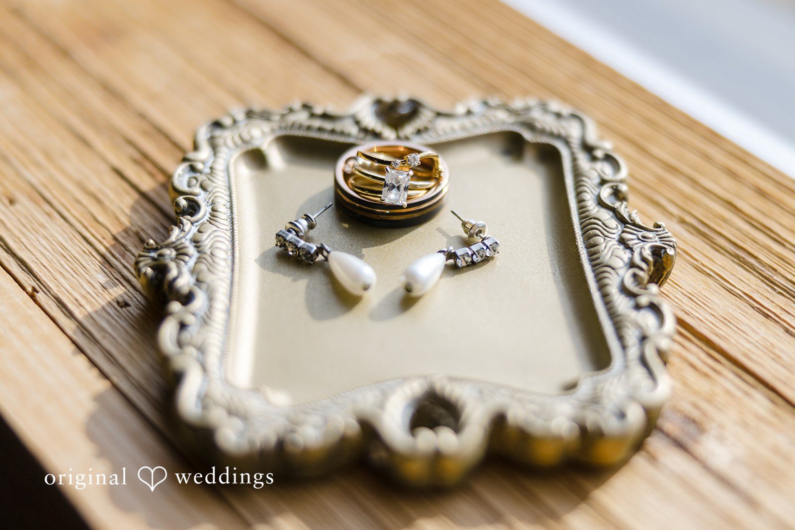 Alia + Lance Ornate gold tray holding jewelry and a wedding ring box.