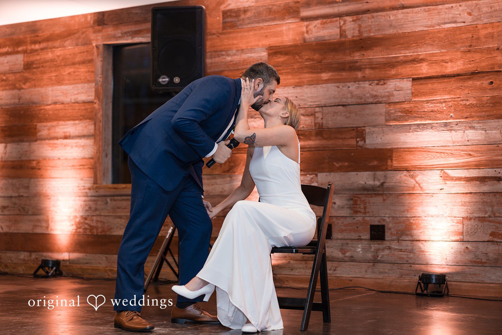 Alia + Lance Groom leaning in to kiss the seated bride during the reception.