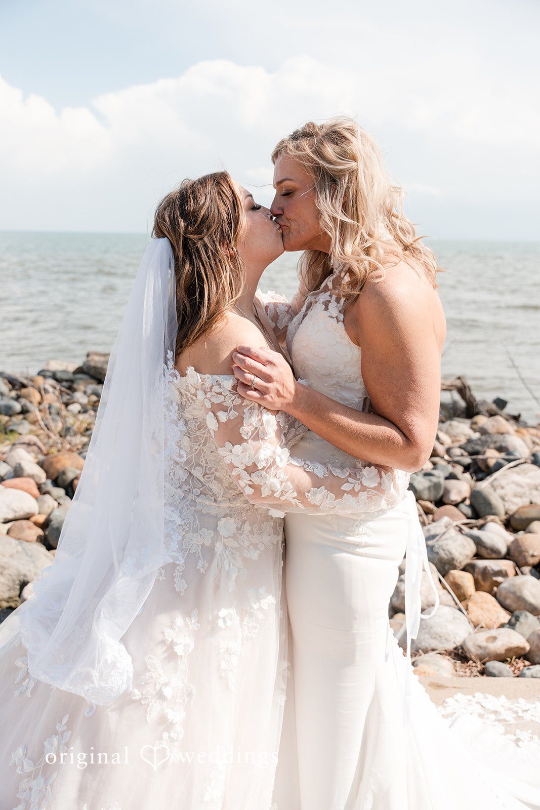 Bride and bride sharing a romantic kiss by the water