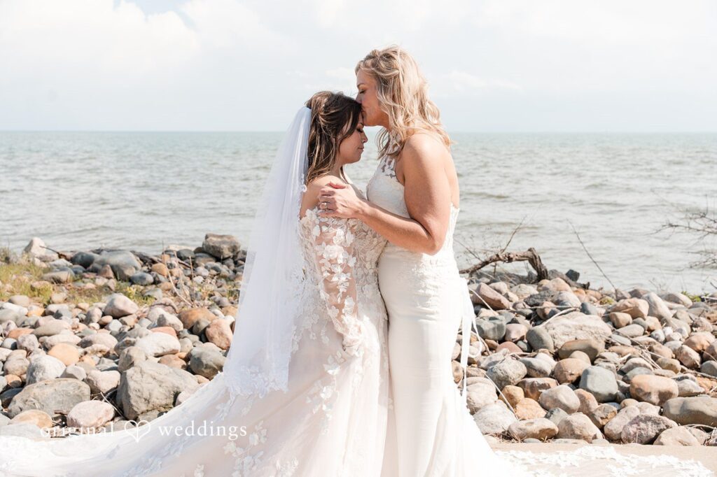 Bride and bride kissing together on the beach at sunset