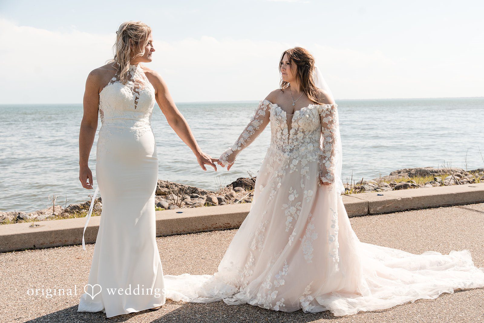 Bride and bride holding hands while walking along the beach