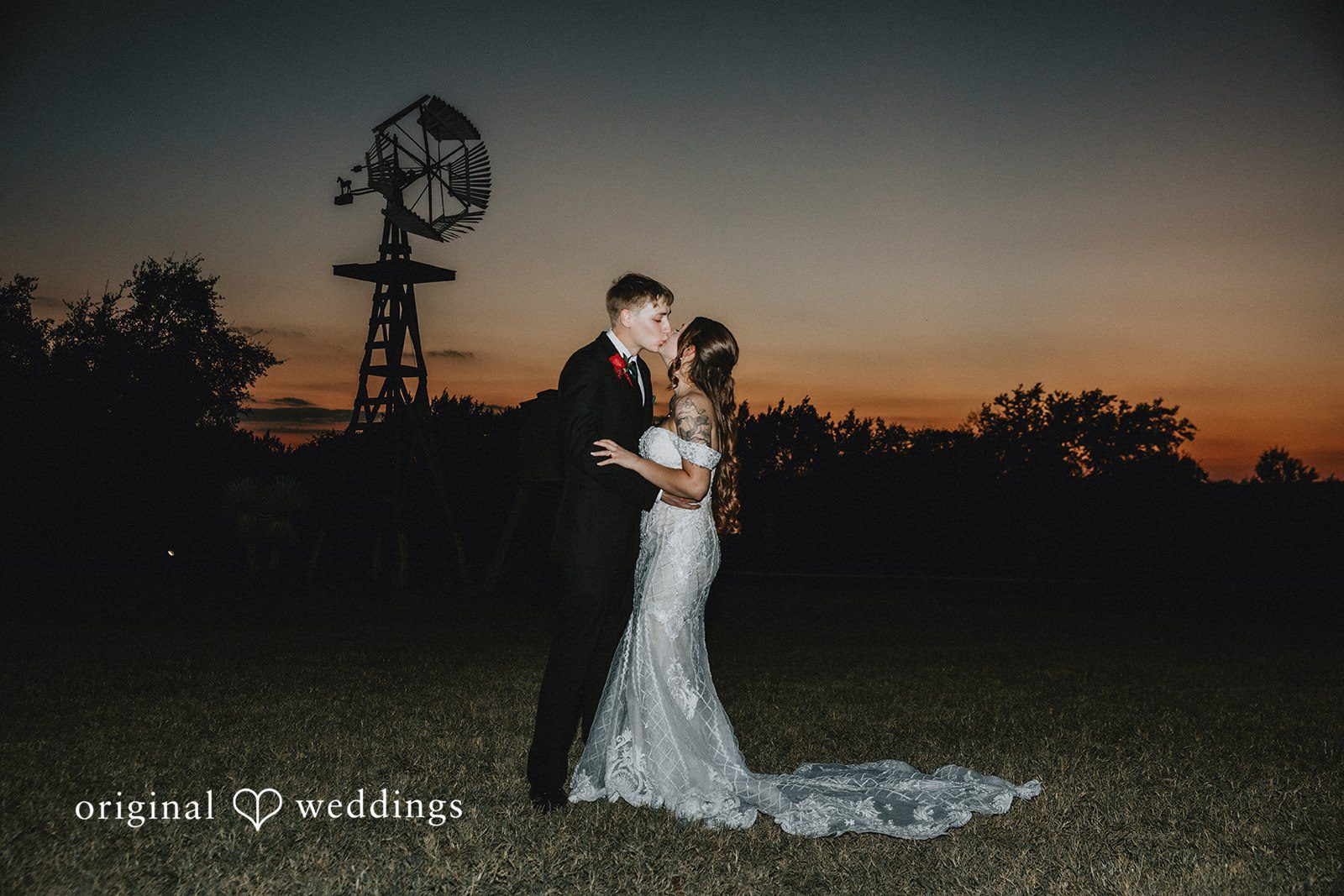 Newlywed couple sharing a kiss during evening wedding photography session