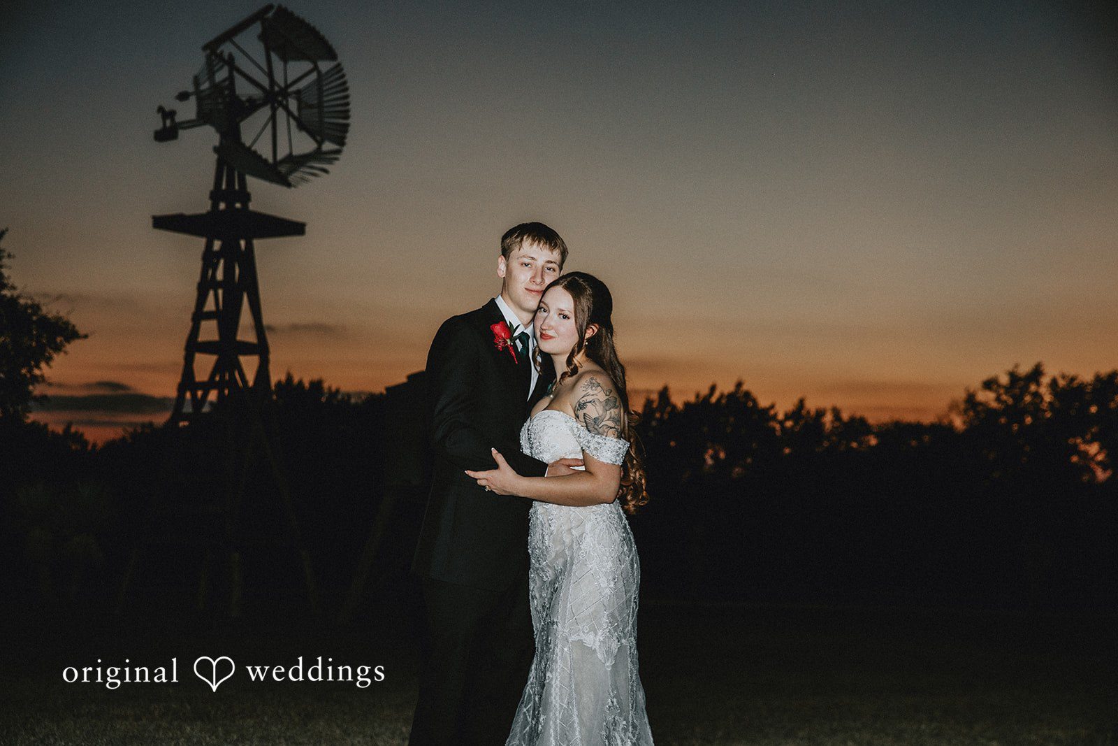 Bride and groom embracing together outdoors during sunset wedding picture