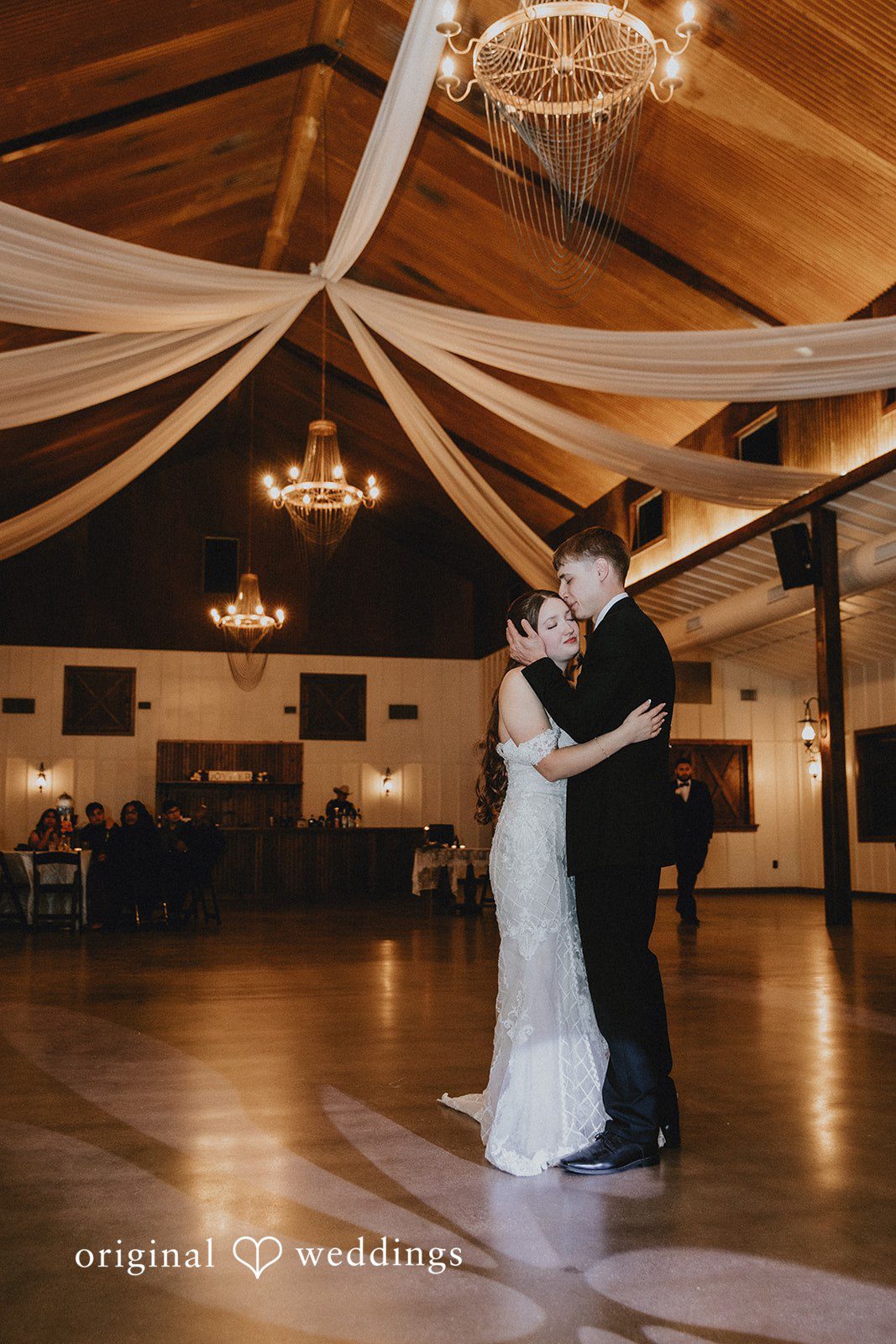 Bride and groom dancing together and groom kissing bride on the forehead