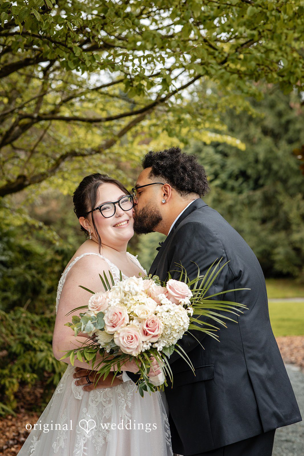 Elegant groom kissing bride’s cheek while she looks ahead at Willows Lodge