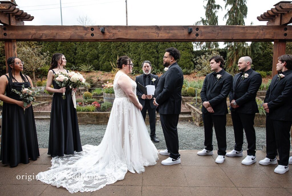 Seattle wedding photographers from Original Weddings capturing bride and groom standing in front of priest looking at each other at Willows Lodge
