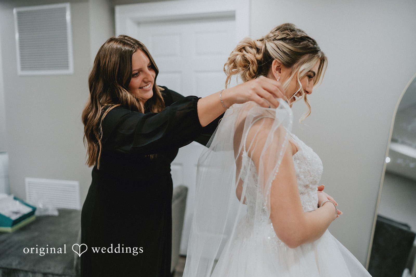 Sarah + Justin A stylist adjusting a veil on a smiling bride.