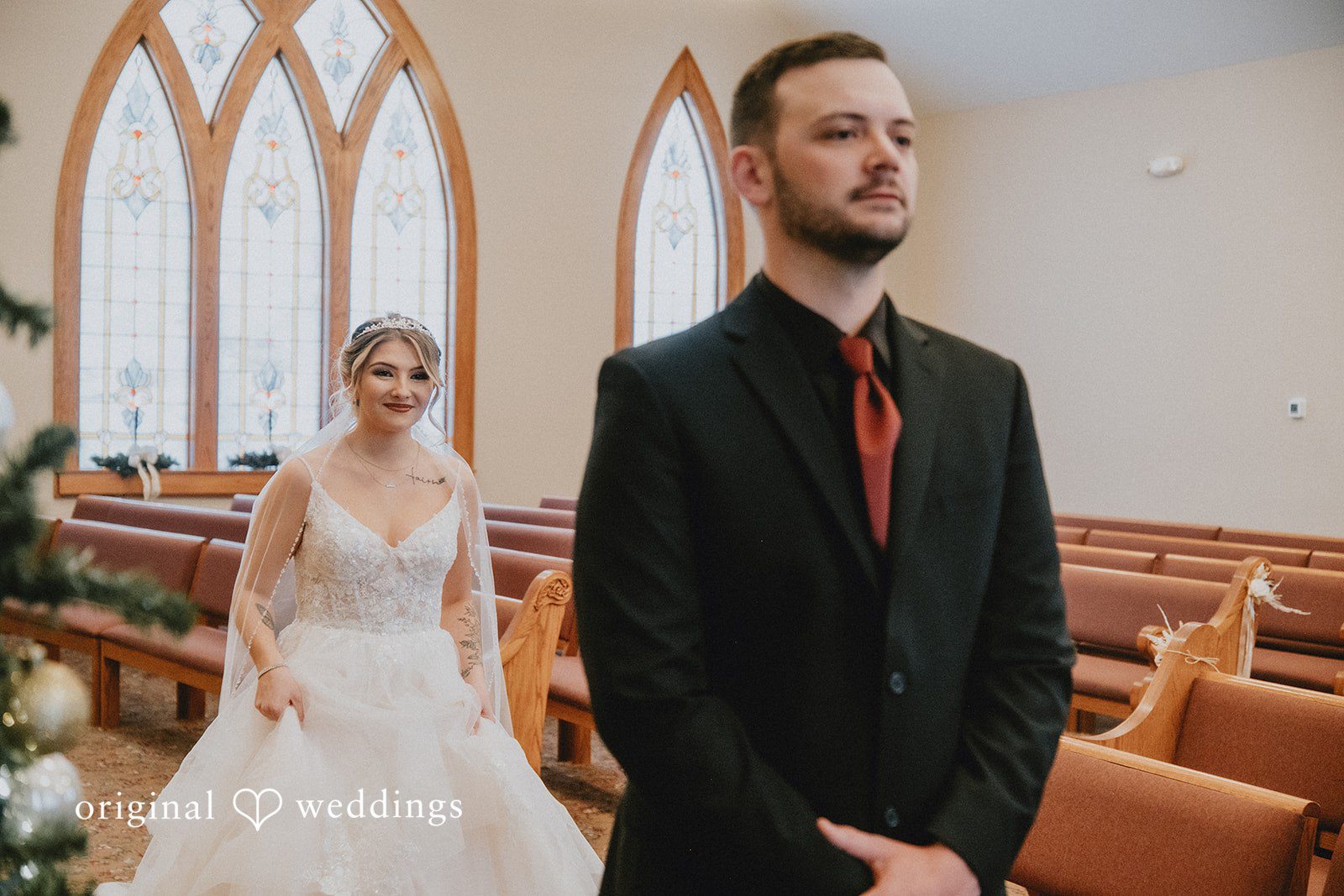 Sarah + Justin The bride walks down the church aisle toward the groom who is waiting at the front.