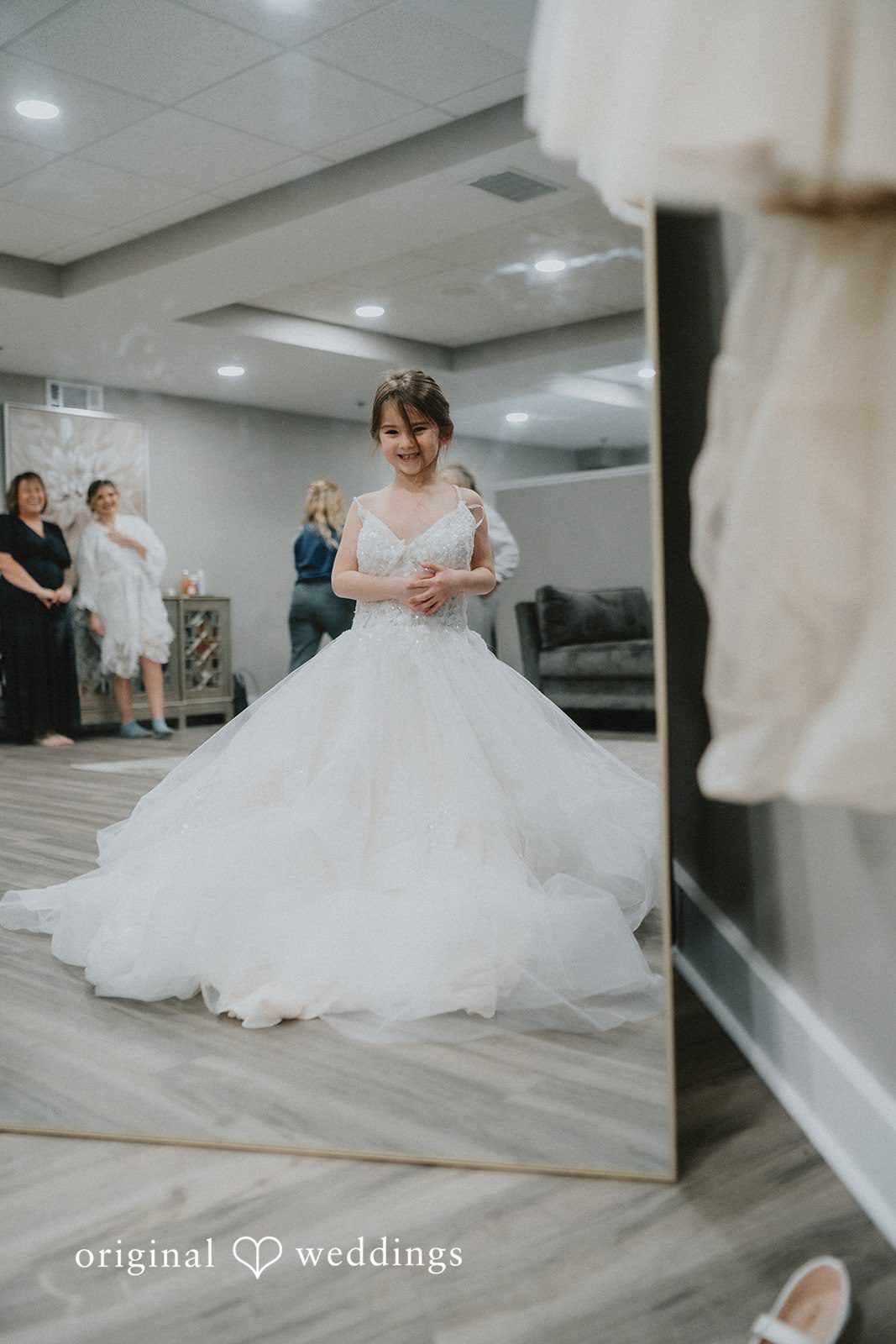 Sarah + Justin A mirror reflection of a smiling young girl wearing a large tulle wedding dress.