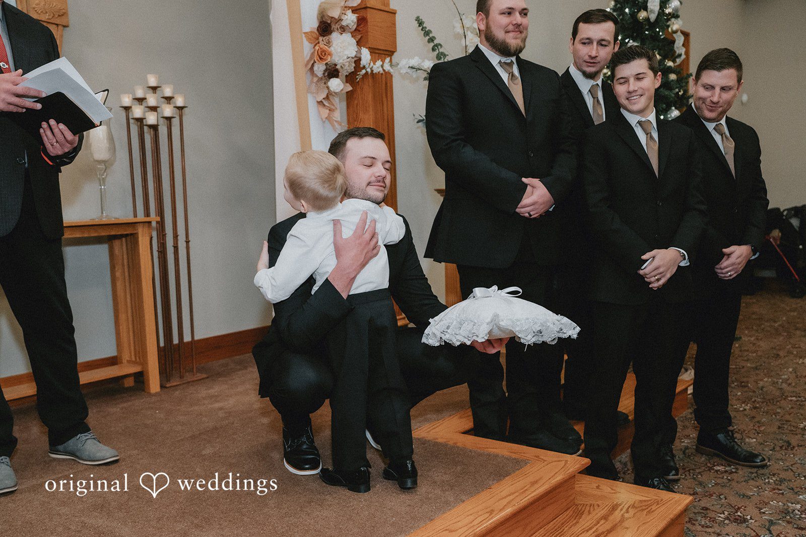 Sarah + Justin A groom and groomsmen in black suits stand together in a church.