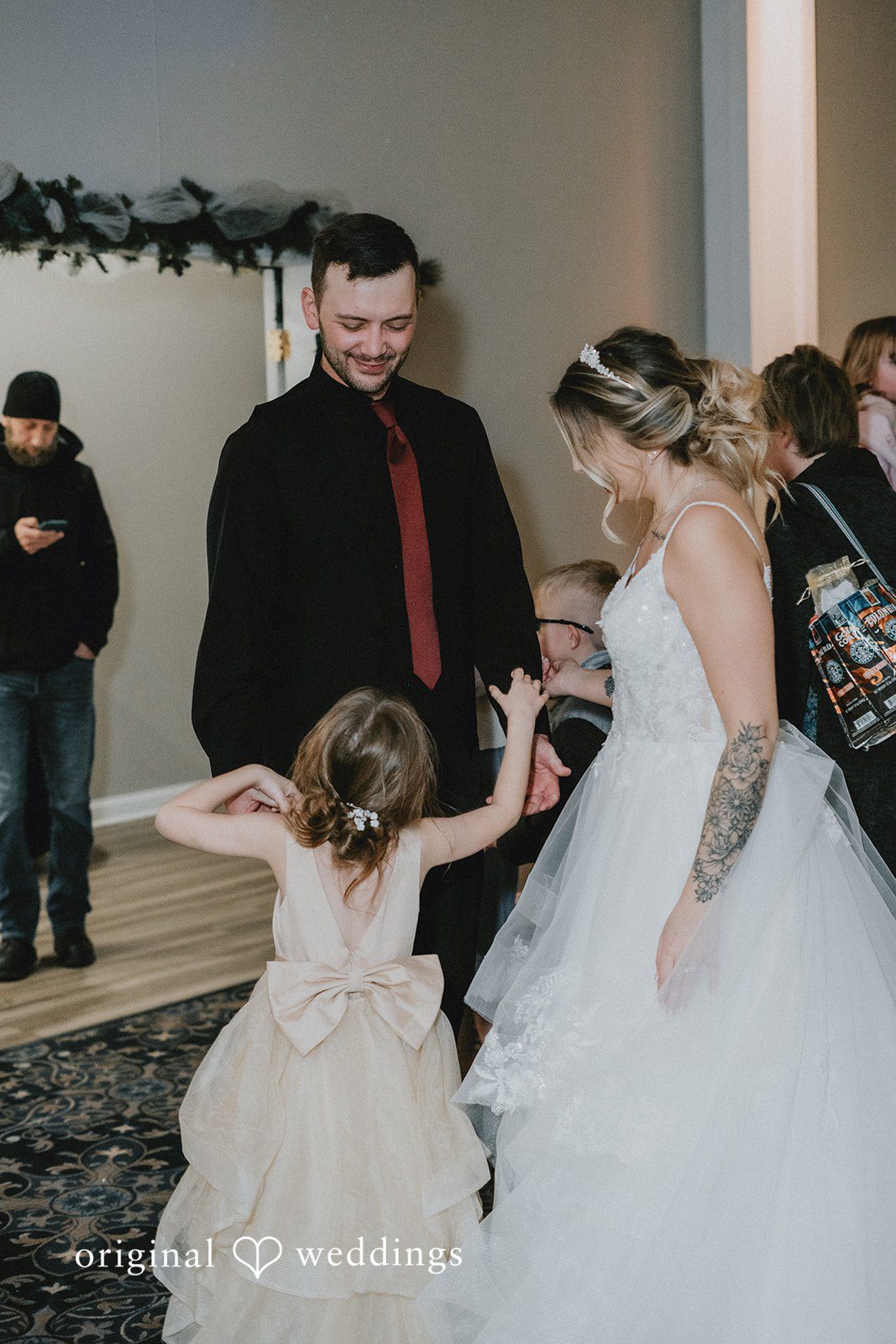 Sarah + Justin A bride and groom hold hands and dance with a young flower girl at their wedding reception.