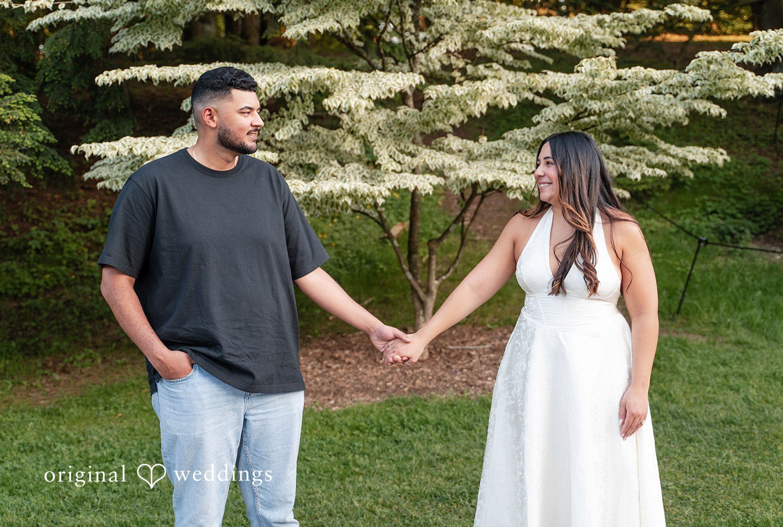 The couple holds hands and shares a sweet smile at Arnold Arboretum captured by Boston engagement photographers from Original Weddings