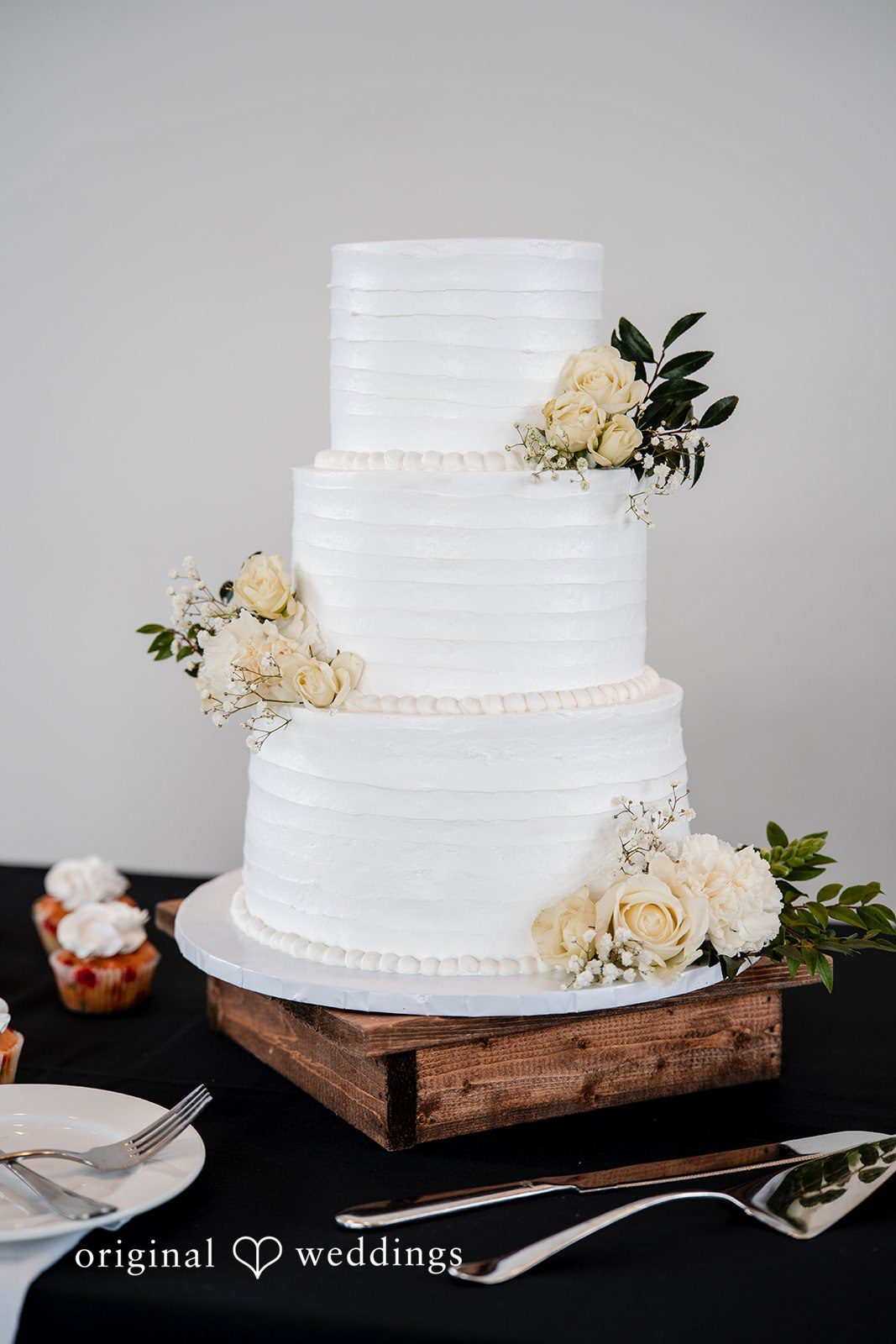 Emily + Miguel An all-white wedding cake adorned with florals