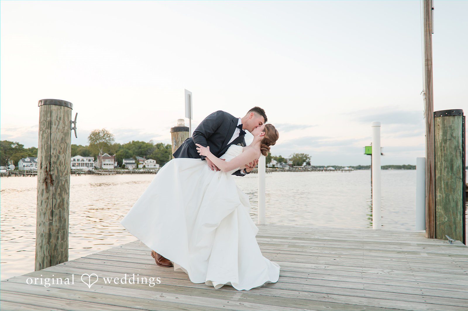Andrew + Paige Bride and groom sharing a kiss on the marina dock at sunset