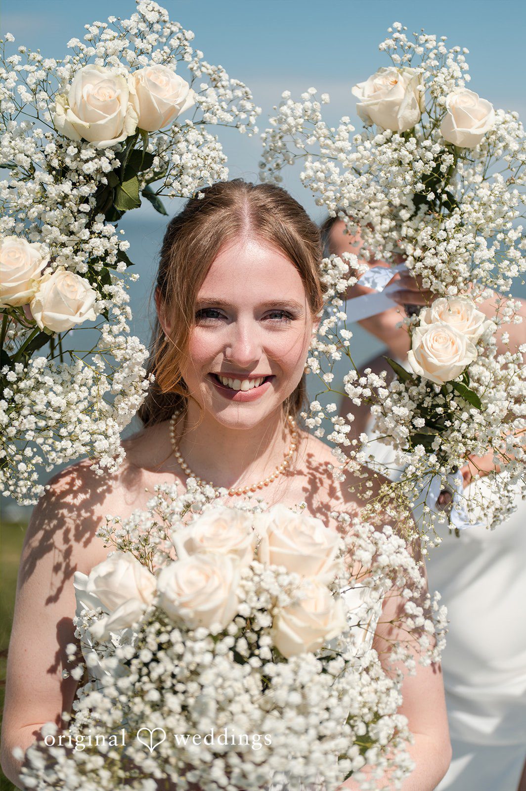 Andrew + Paige Bride posing among floral wedding decorations