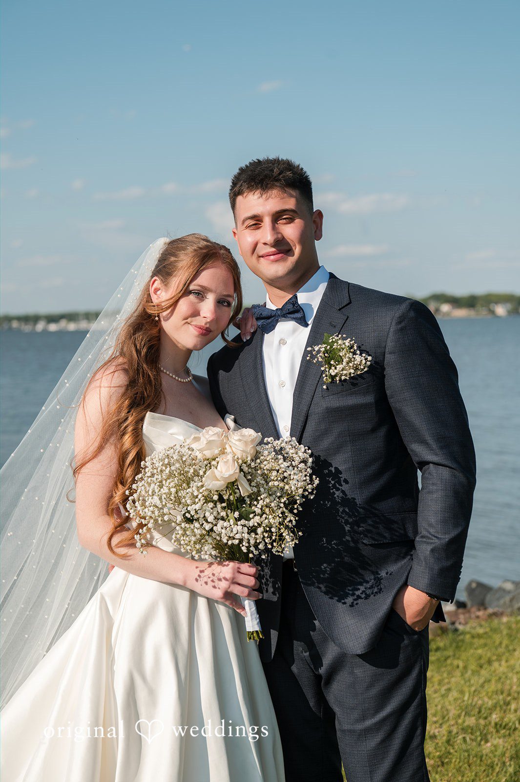 Andrew + Paige Full-length portrait of the bride and groom on the waterfront lawn