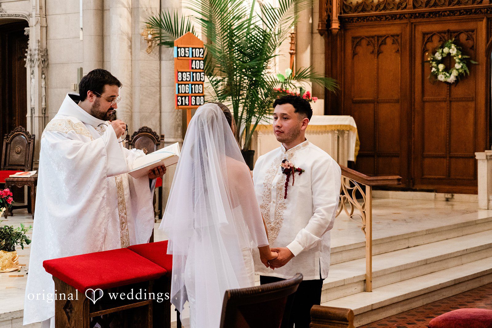 Michael + Maria Bride and groom holding hands during their church wedding ceremony with the officiant.