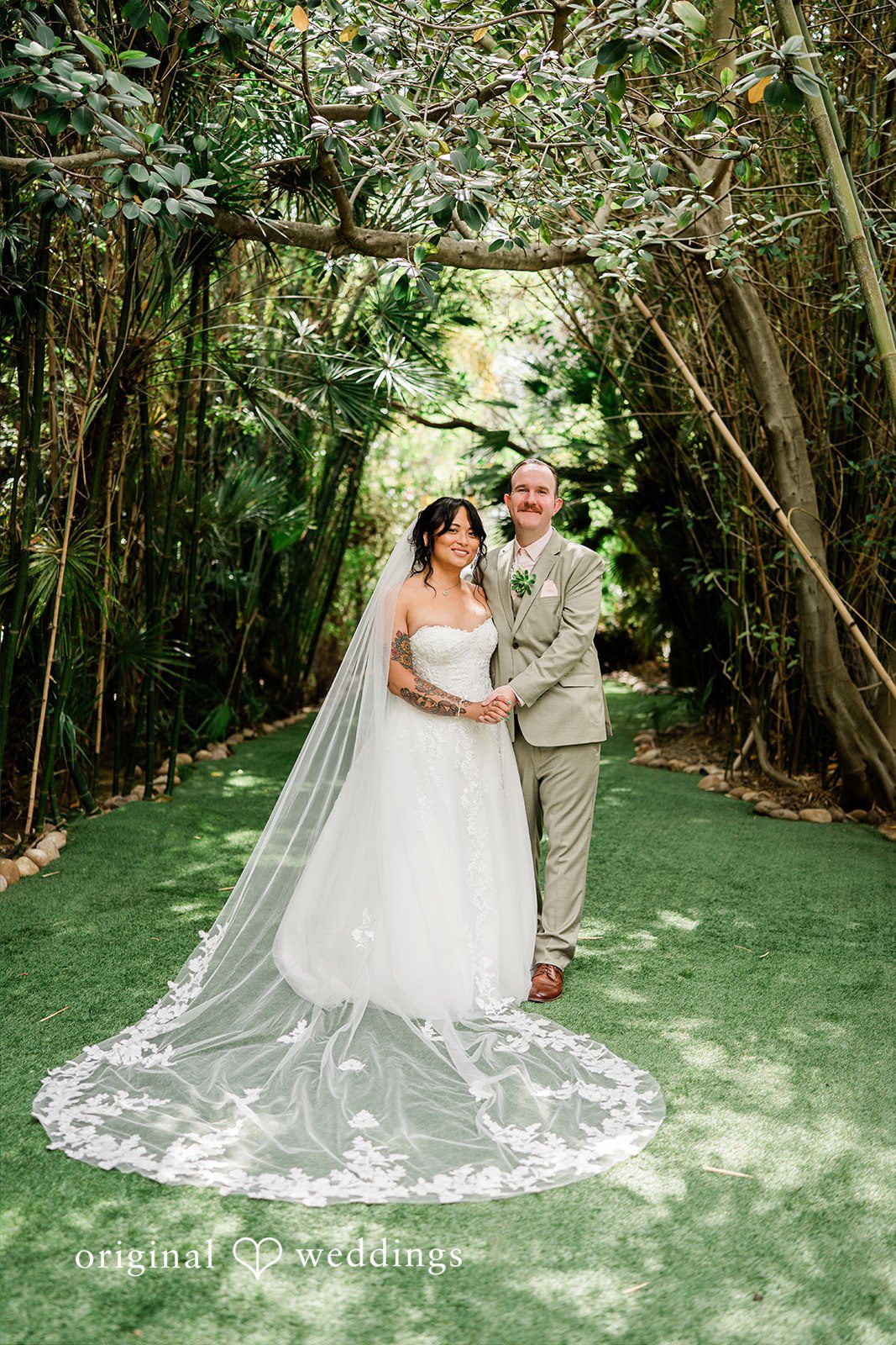 Mae + Nicholas Bride and groom posing beneath Botanica’s lush garden canopy with a flowing veil.