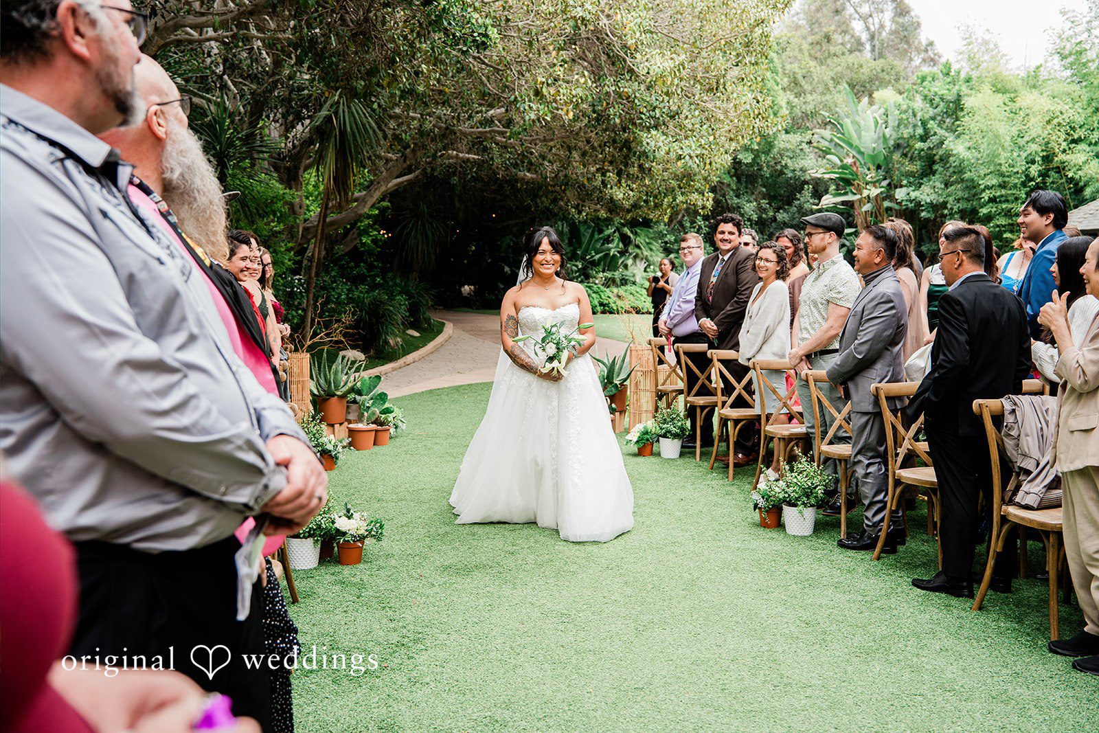 Mae + Nicholas Bride walking down the aisle at Botanica surrounded by family and friends.