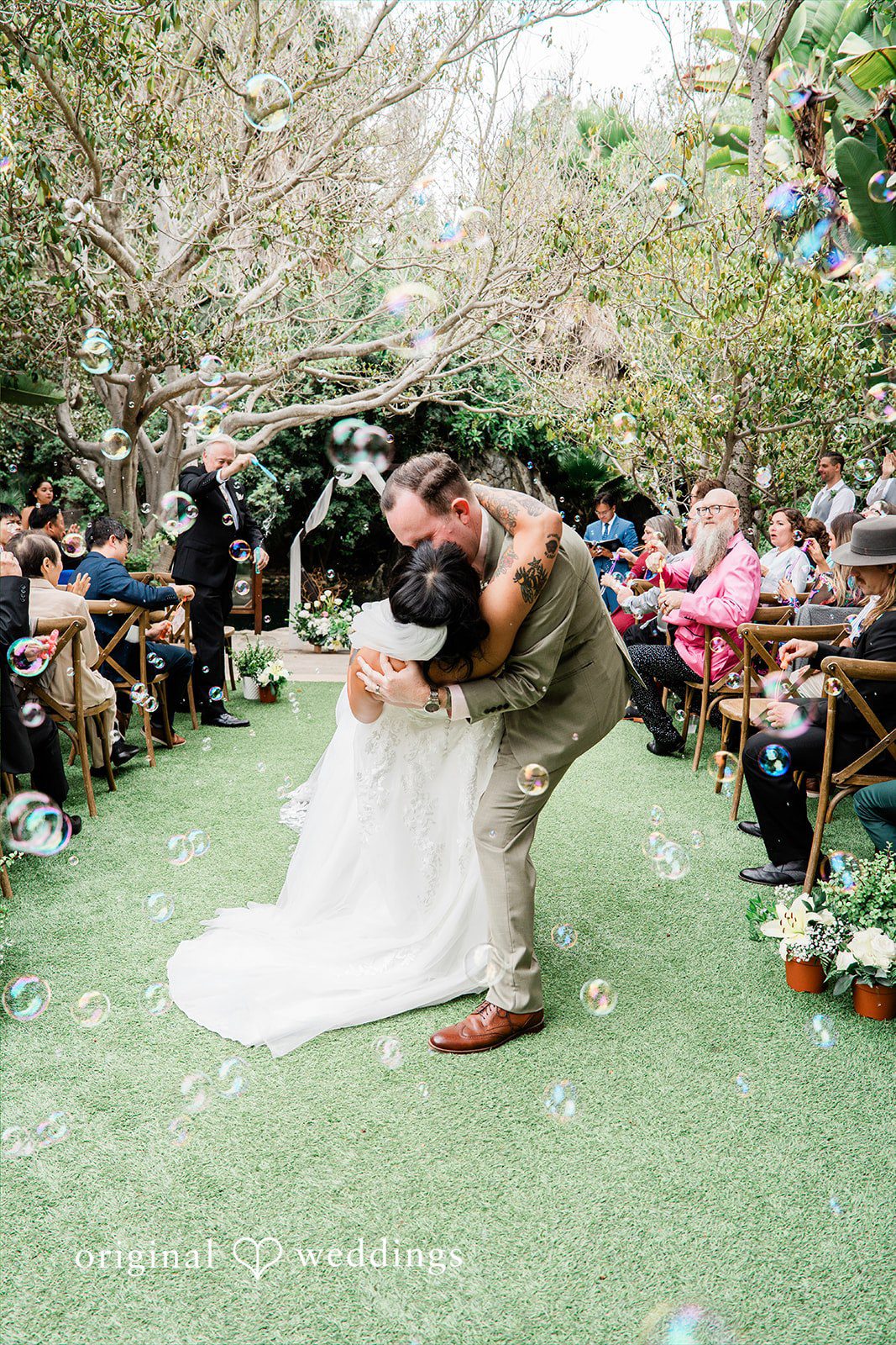 Mae + Nicholas Bride and groom sharing a celebratory kiss under bubbles at Botanica.