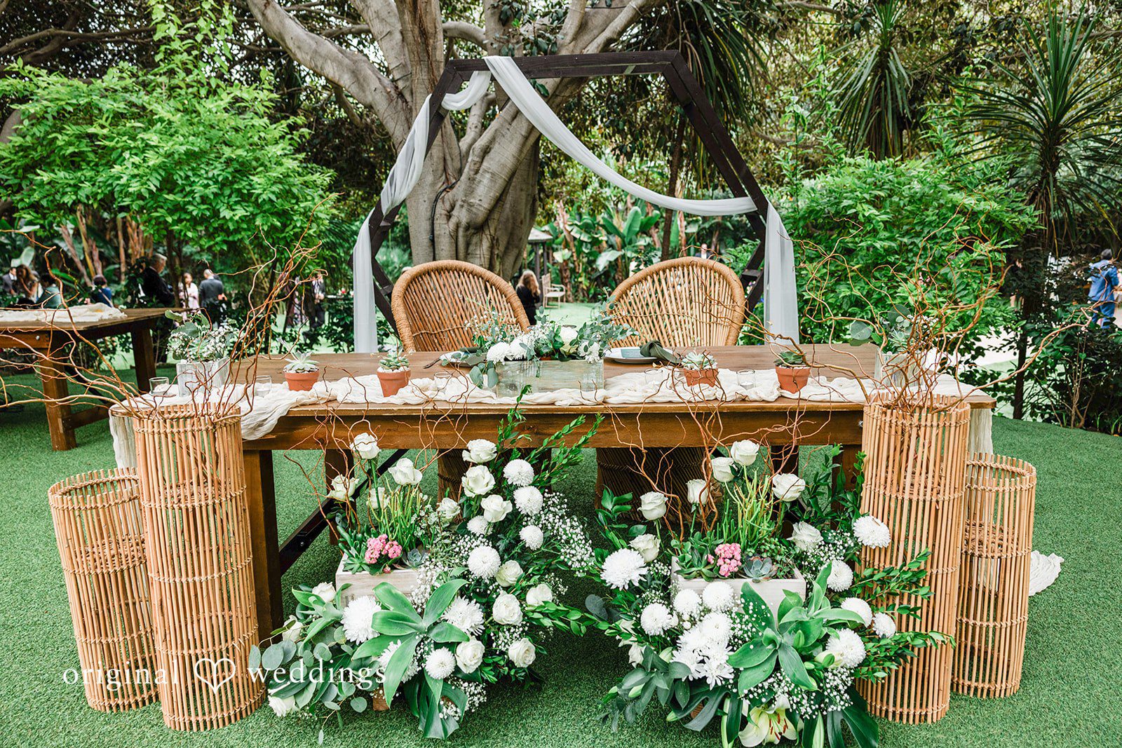 Mae + Nicholas Sweetheart table with floral décor and rattan chairs ready for the reception.